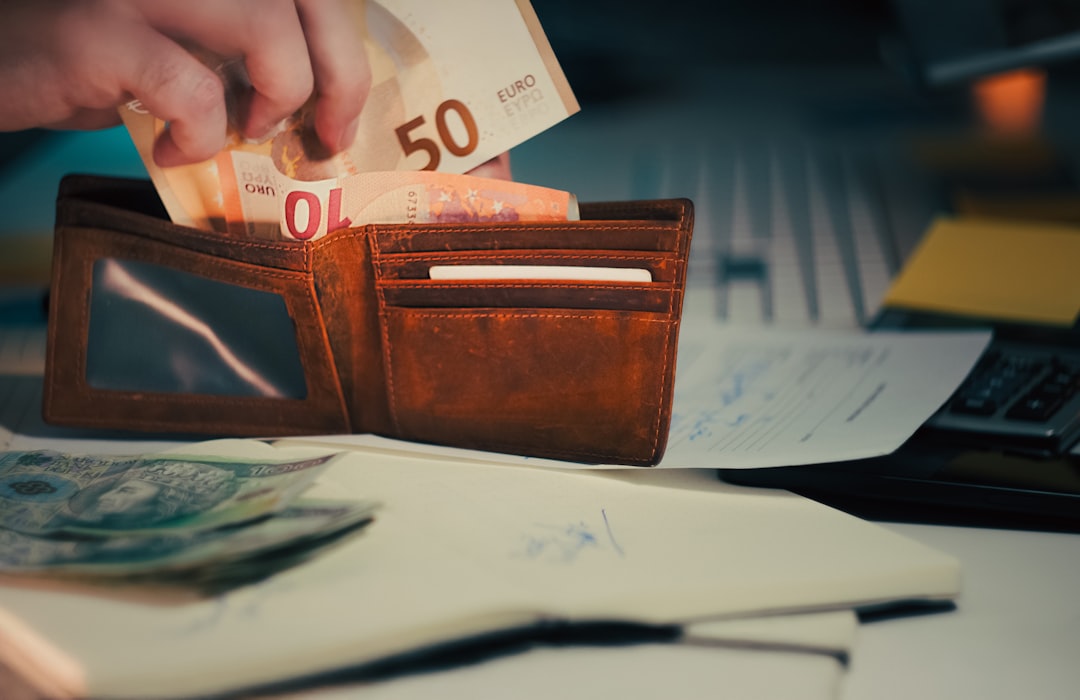 Hand taking euro bills from wallet business finance desk. Close-up of man removing 50 euro note from worn leather wallet